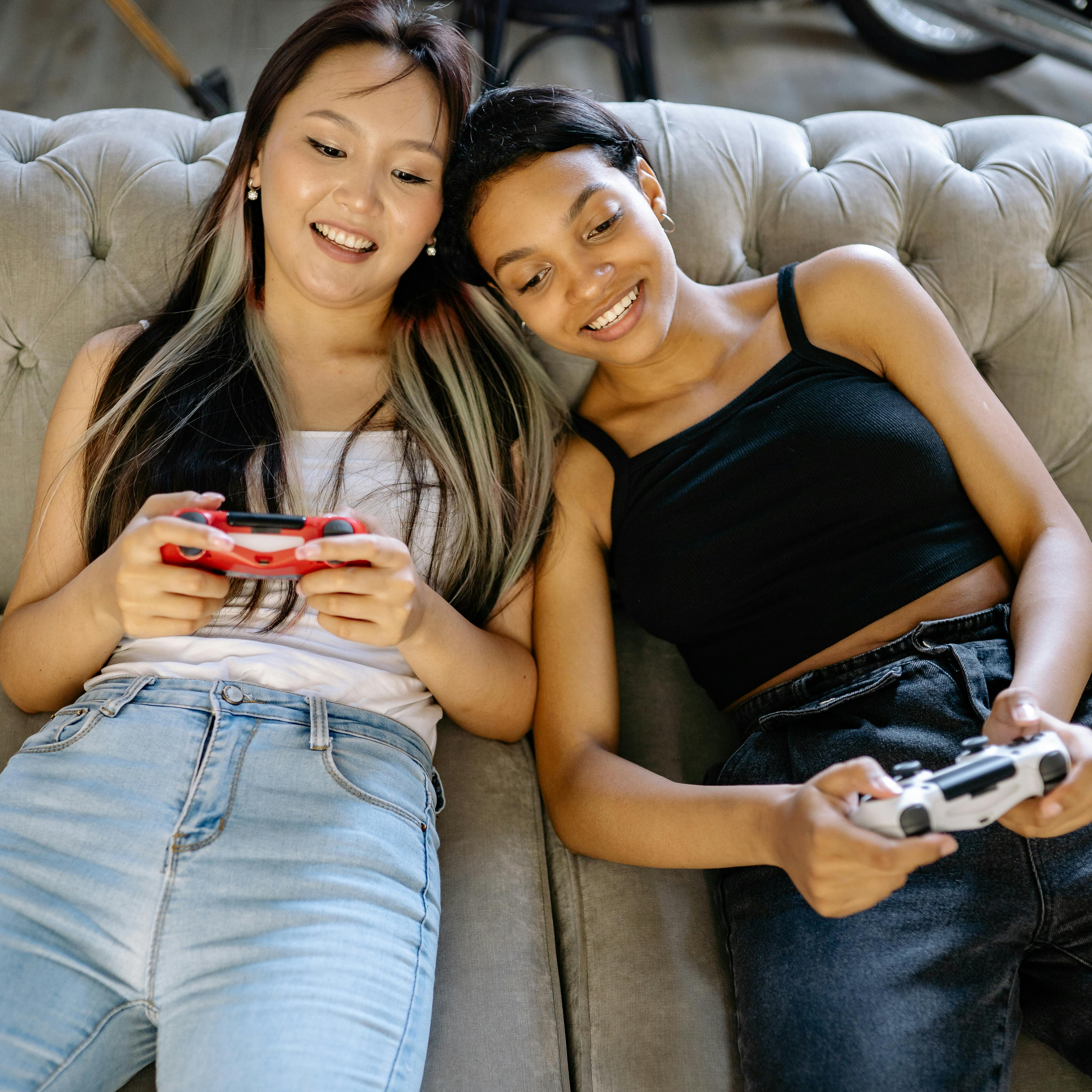Two Women Playing Video Games while Sitting on the Sofa