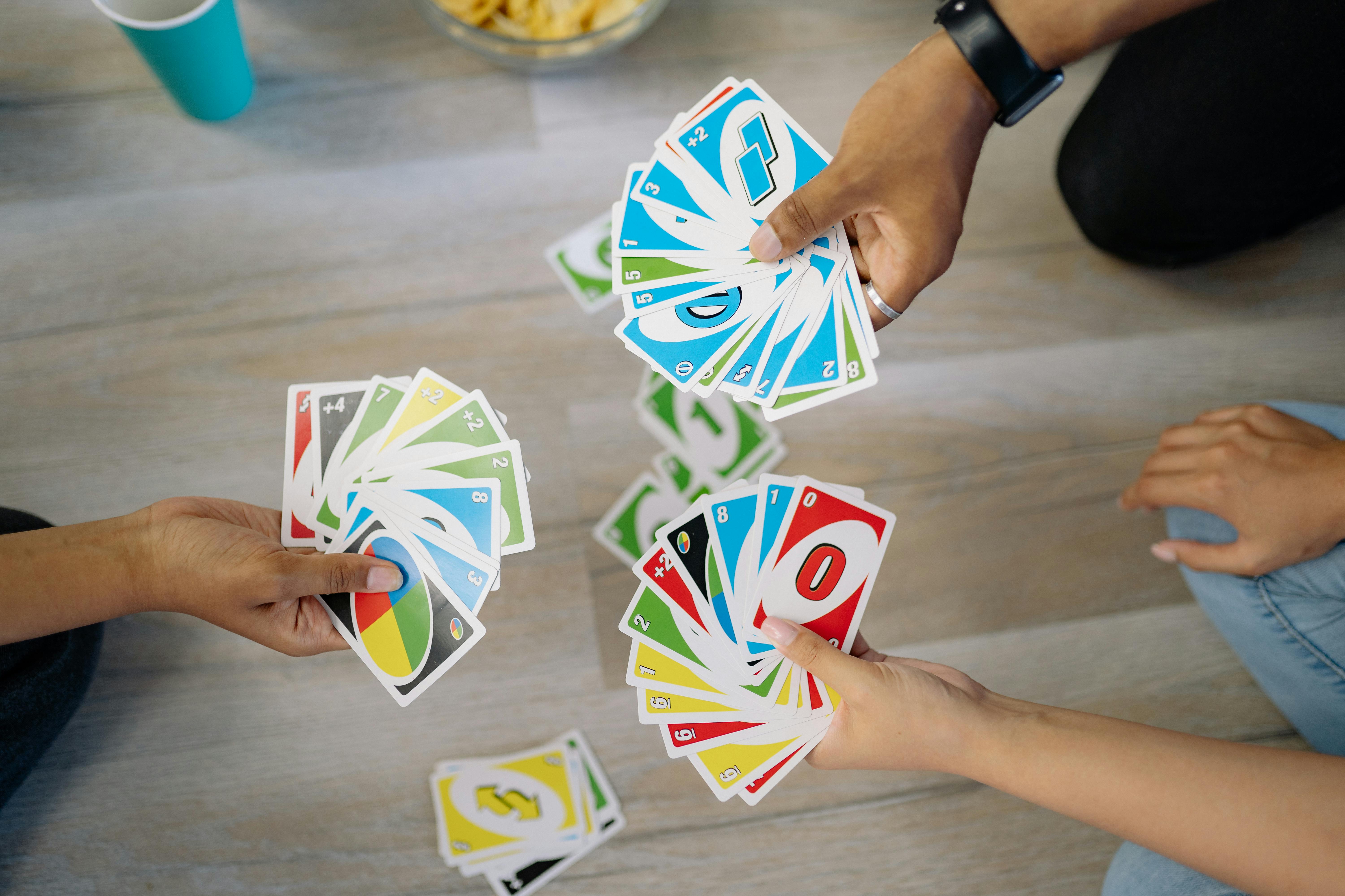 A group of hands holding out Uno cards.
