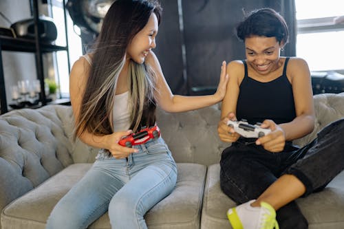 Two Women Playing Video Games while Sitting on the Sofa