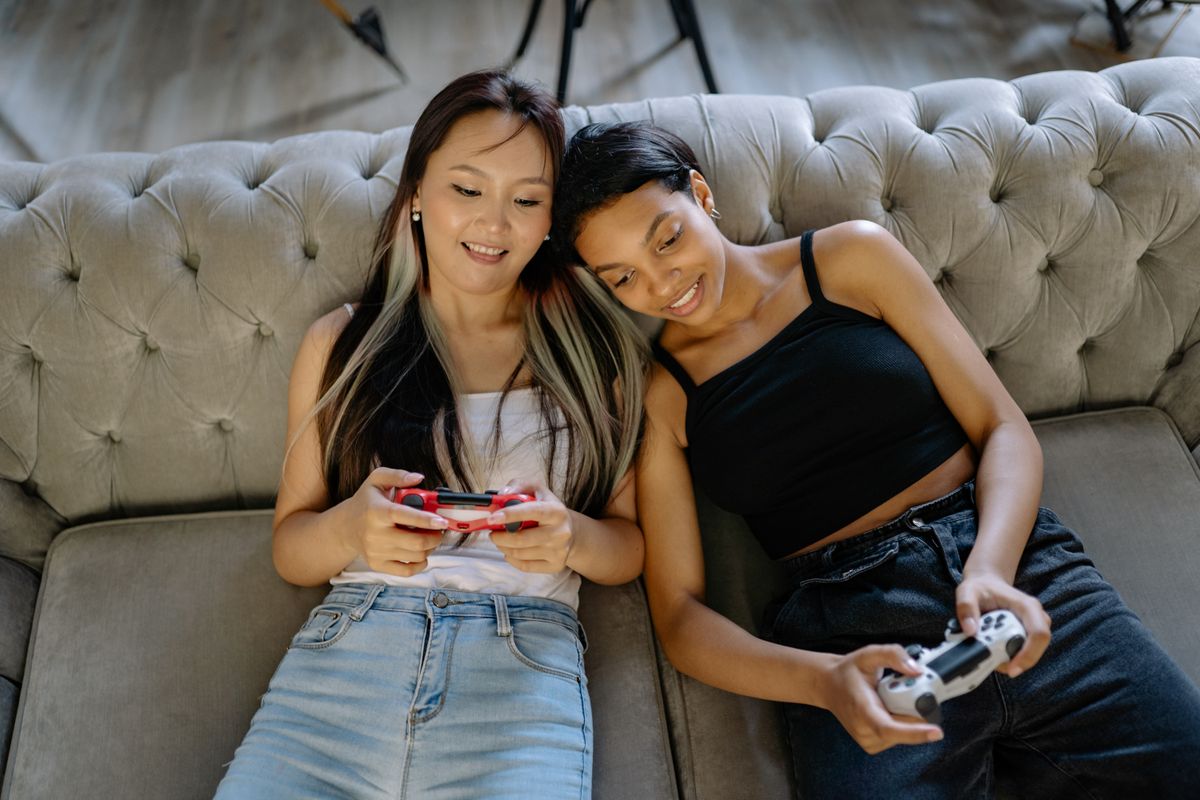 Friends playing a multiplayer video game together on a sofa