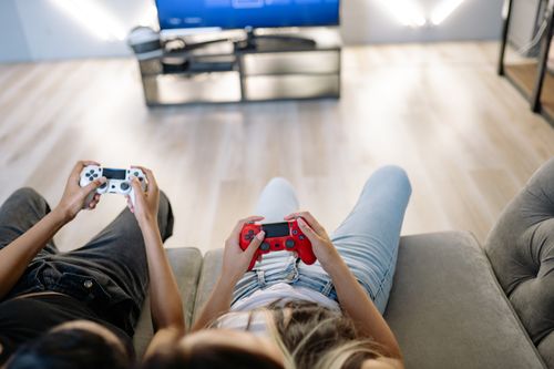 Free Two friends playing video games together indoors with game controllers. Stock Photo