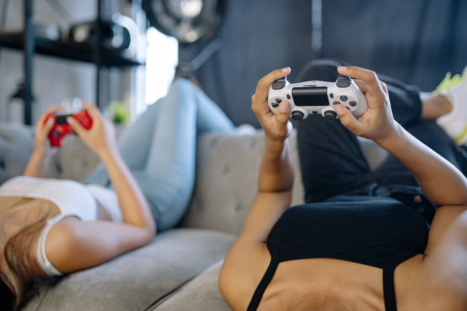 居心地の良いリビングルームでくつろぎながらビデオゲームをしている二人の女性。