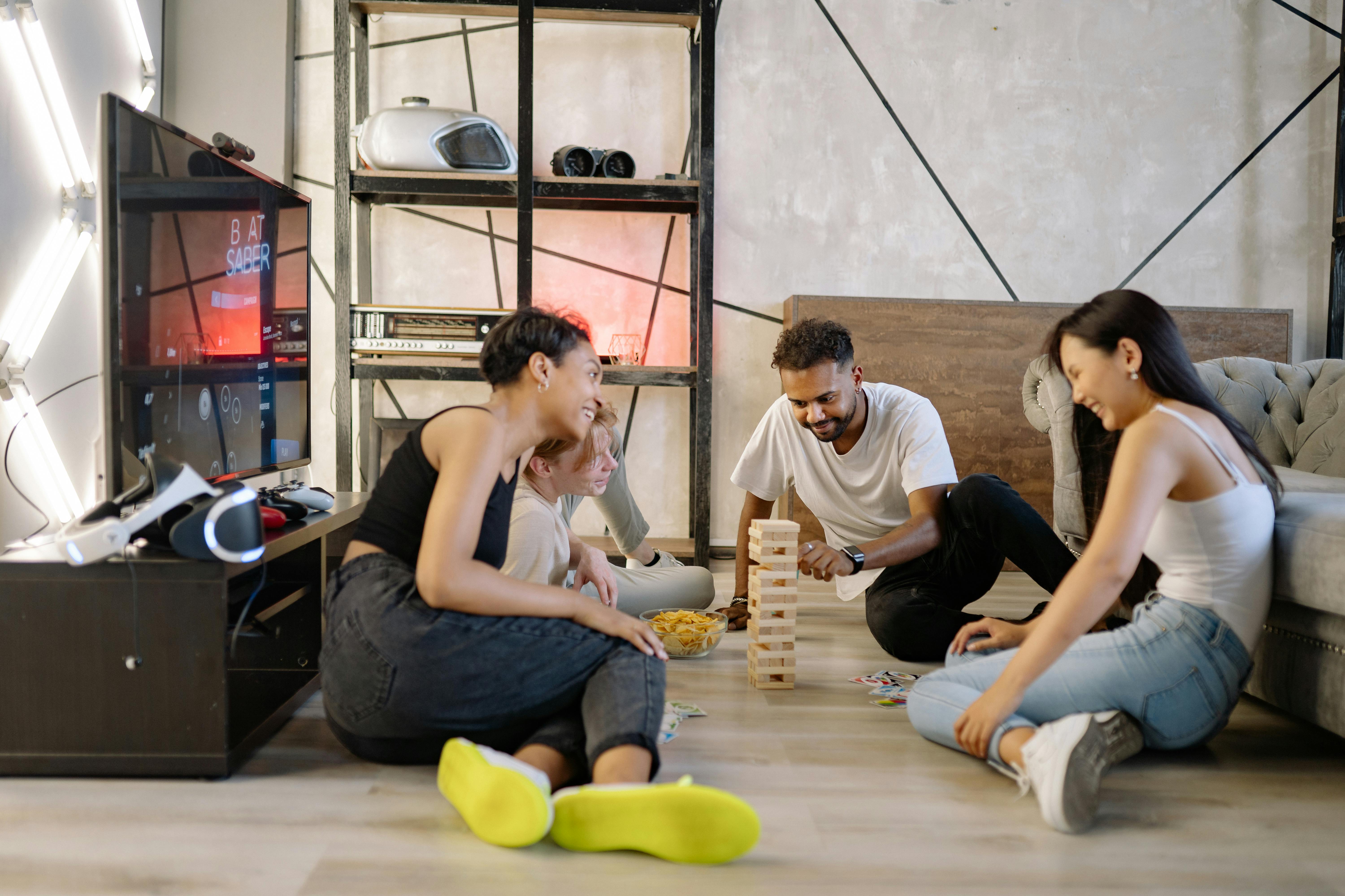 A happy adult couple laughing and bonding while engaging in a playful, childlike activity like building with toy blocks or coloring together on the living room floor.