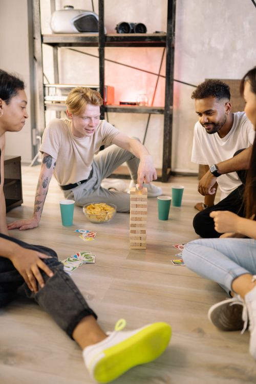 Free A group of friends enjoying a fun indoor game night playing Jenga and card games. Stock Photo
