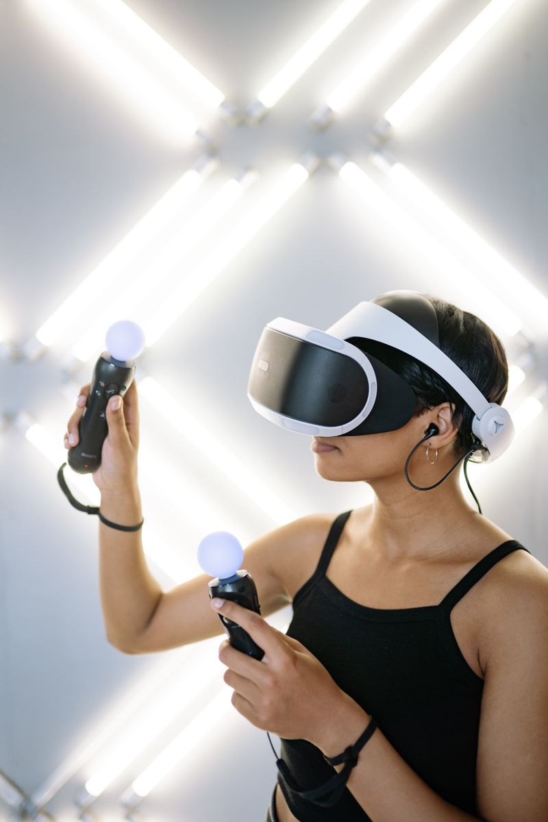 Young woman using virtual reality headset and controllers indoors.