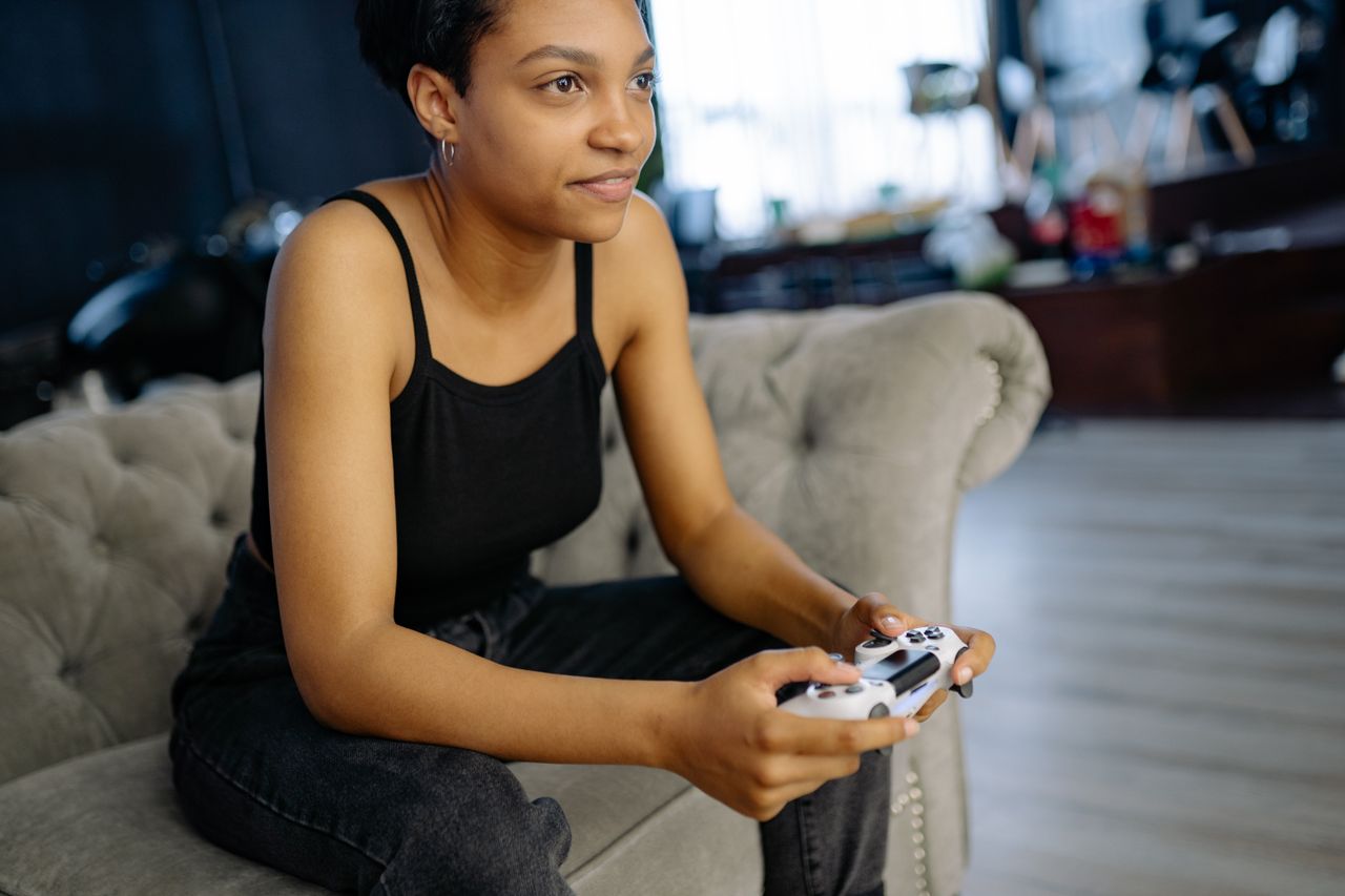 woman enjoying leisure time playing video games at home on a cozy sofa
