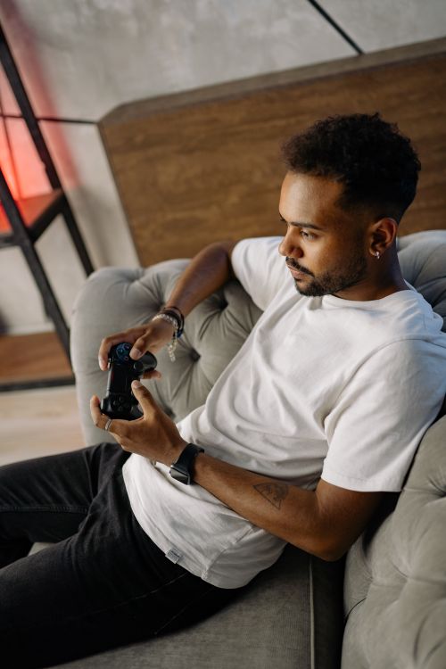 Free Young man sitting on sofa, focused on video gaming with a controller. Stock Photo