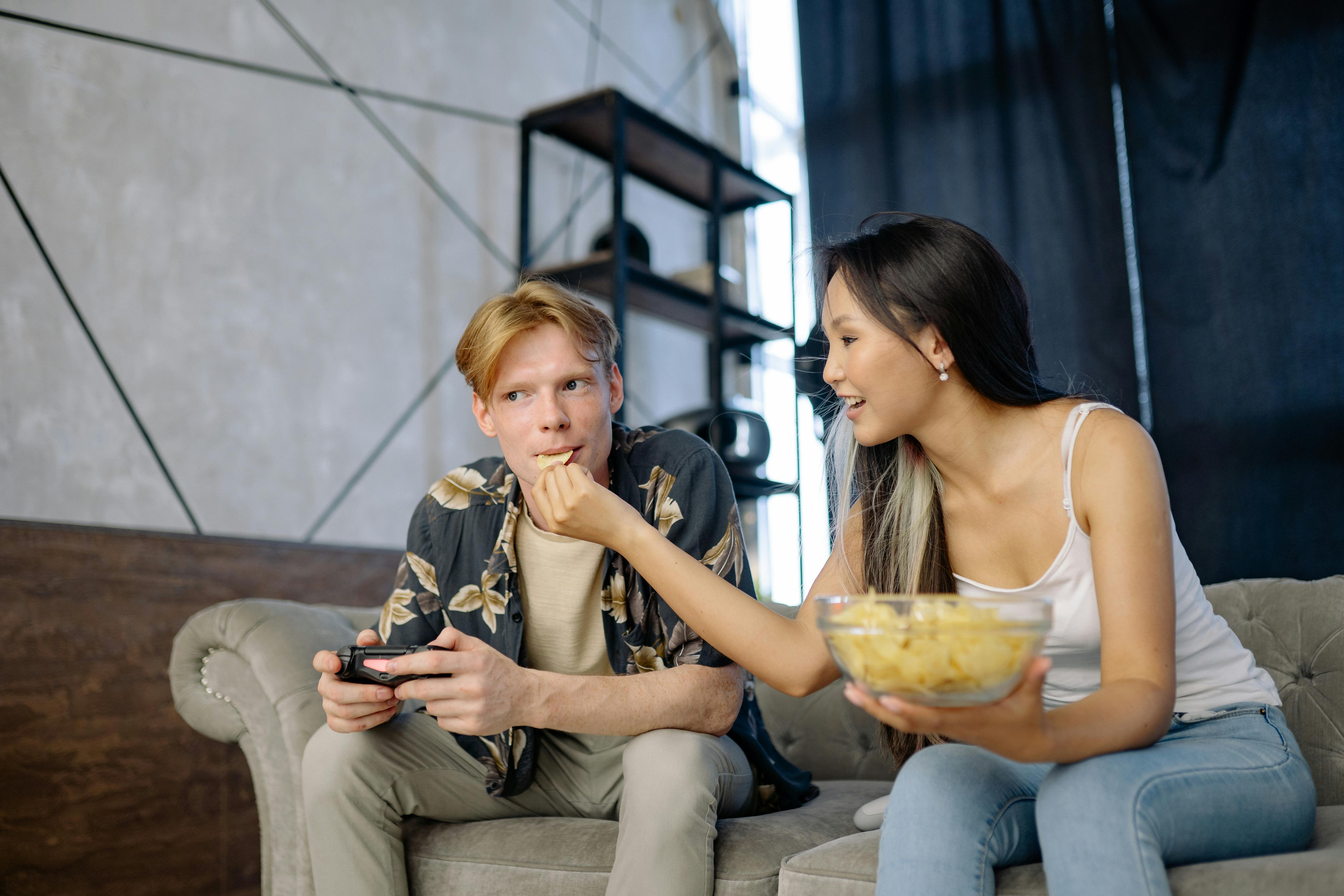 a woman feeding a man with potato chip