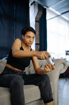 Young woman intently gaming at home, gripping a controller on a cozy couch.