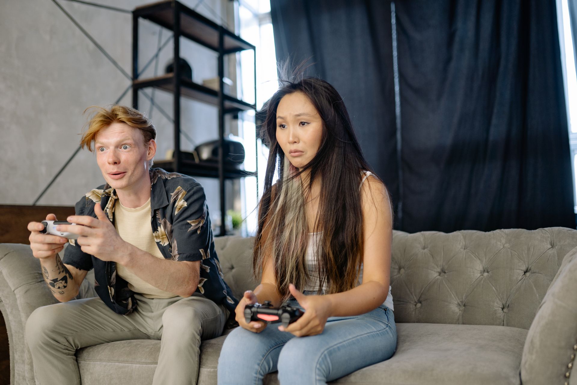 A Man and a Woman Playing Video Games while Sitting on the Sofa