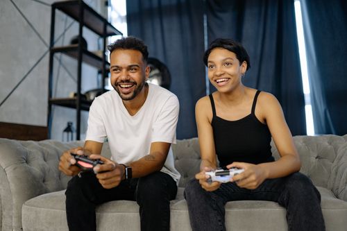 Free Two young adults have fun playing video games on a sofa, enjoying leisure indoors. Stock Photo