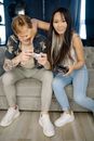 Woman in Blue Denim Jeans Sitting Beside Woman in Brown and Black Floral Shirt