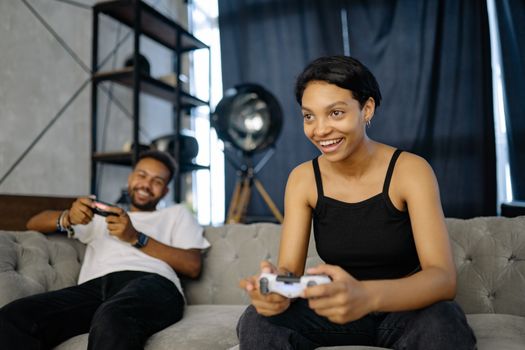 Two friends having fun playing video games indoors, sitting on a comfortable couch.
