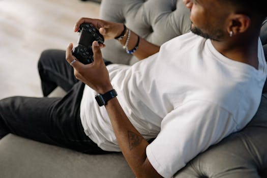 A man casually gaming on a couch, holding a controller. Indoor setting with a focus on leisure.