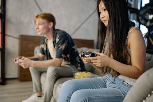 Young adults enjoying leisure time playing video games together on a couch, indoors.