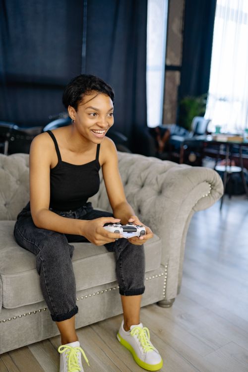 Free Happy young woman playing video games on the couch at home. Leisure and entertainment indoors. Stock Photo