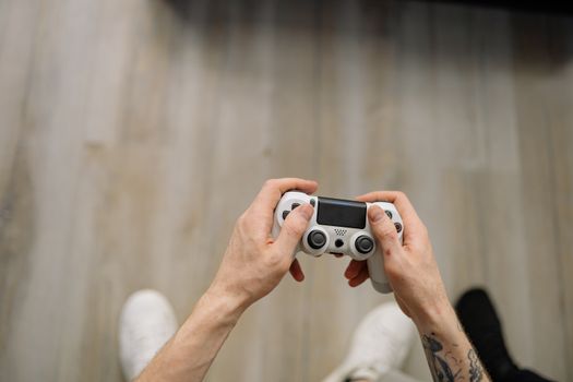Overhead shot of hands with tattoos holding a game controller, ready for gaming.