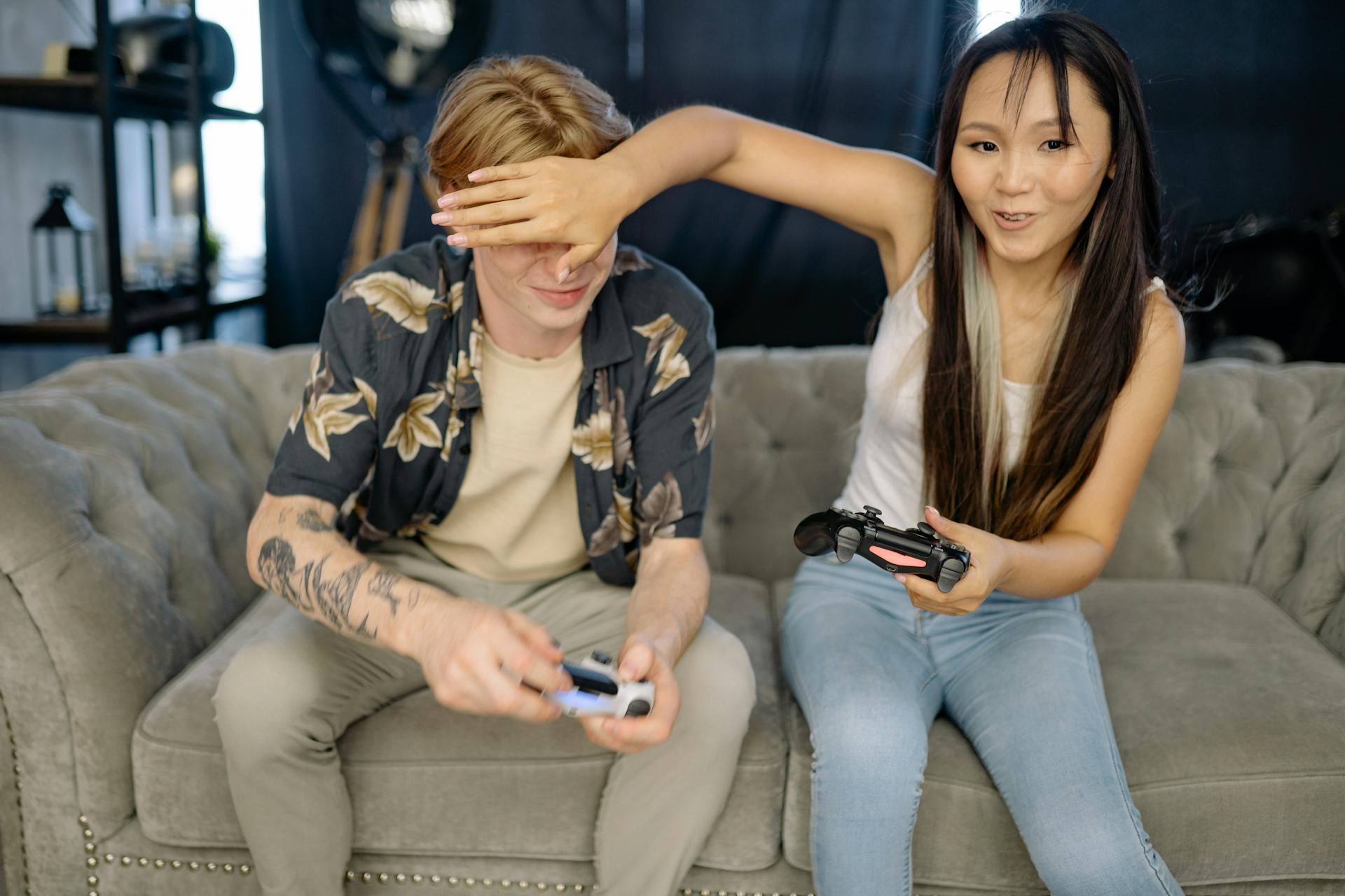 A Man and a Woman Playing Video Games while Sitting on the Sofa