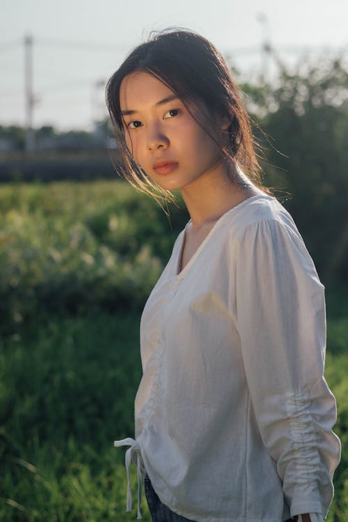 Woman Wearing White Long Sleeve Shirt Standing on Green Grass