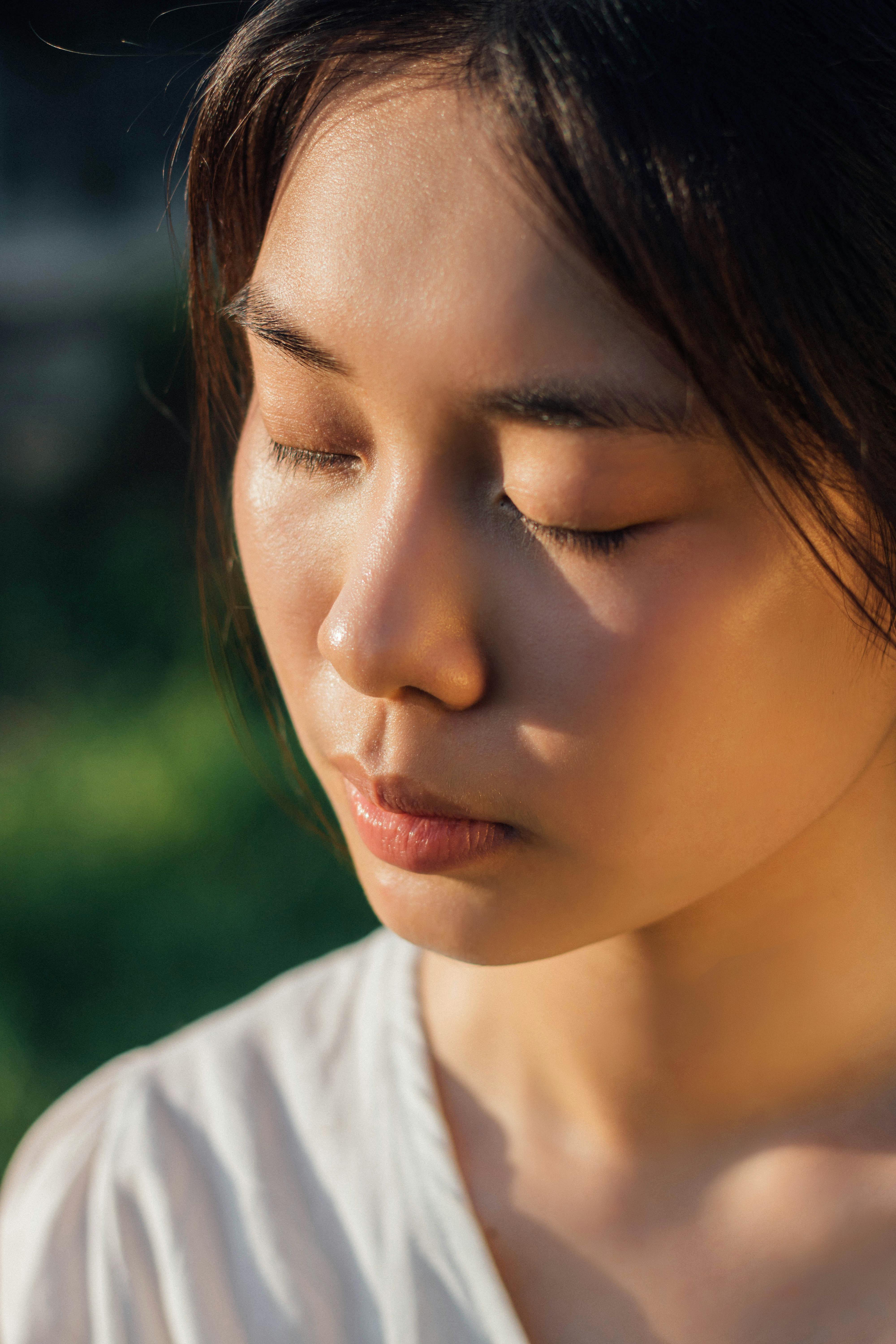 Close-up shot of an adult woman with closed eyes, enjoying the outdoors in natural light.