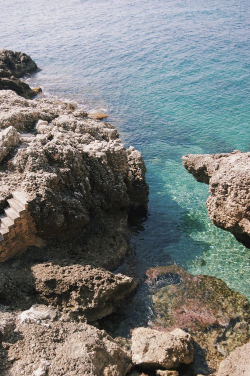 Free Explore this serene seaside beauty with clear blue waters and rugged rock formations. Stock Photo