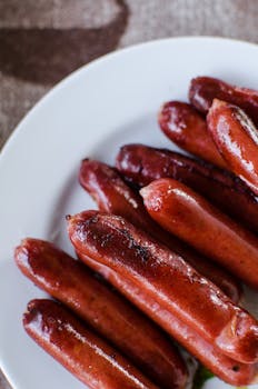 Close-up of deliciously grilled sausages served on a white plate, perfect for a summer meal.