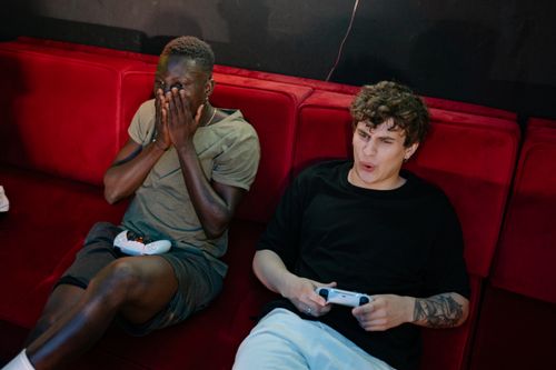 Free Two friends intensely focused on a video game indoors, showcasing emotion. Stock Photo
