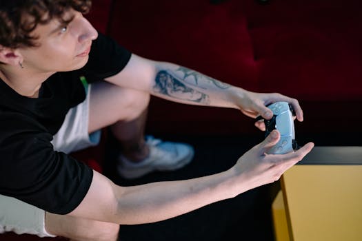 Focused young man playing video games indoors using a wireless controller, sitting on a sofa.