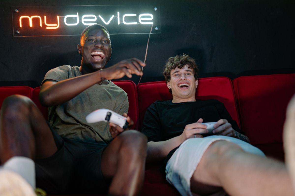 Two friends playing video games together on a couch