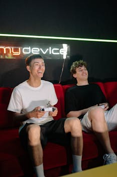 Two friends enjoying video games indoors with neon sign backdrop.