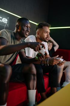 Group of diverse friends playing video games indoors, enjoying a fun and engaging gaming session.