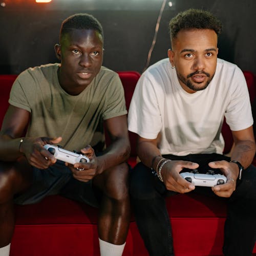 Men Sitting on the Couch while Playing Video Games