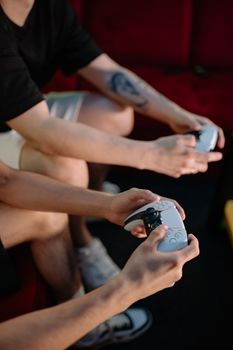 Close-up of friends playing video games indoors with wireless controllers.