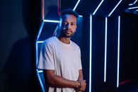 Man in White Crew Neck T-shirt Standing Beside Blue Metal Wall