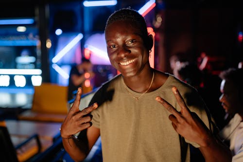 Person in Brown Crew Neck Shirt Doing Peace Sign 