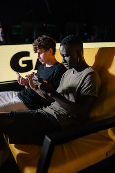 Two men intensely focused on gaming with mobile phones while sitting on a sofa.