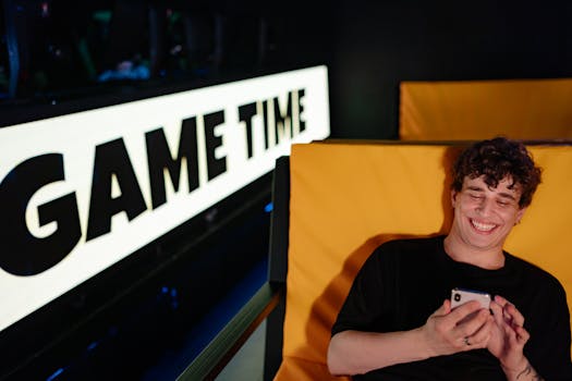 Smiling young man gaming on smartphone in a cozy indoor setting with 'Game Time' sign.