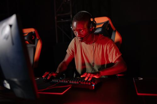 Free Focused gamer playing online with headset and red lighting environment. Stock Photo