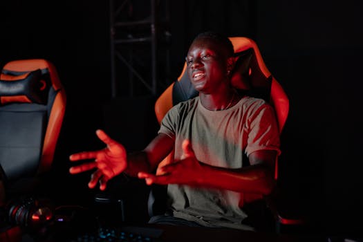 A young man passionately reacting while sitting in a gaming chair indoors.