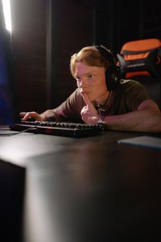 A concentrated gamer using a computer and headset, deeply engaged in gaming.