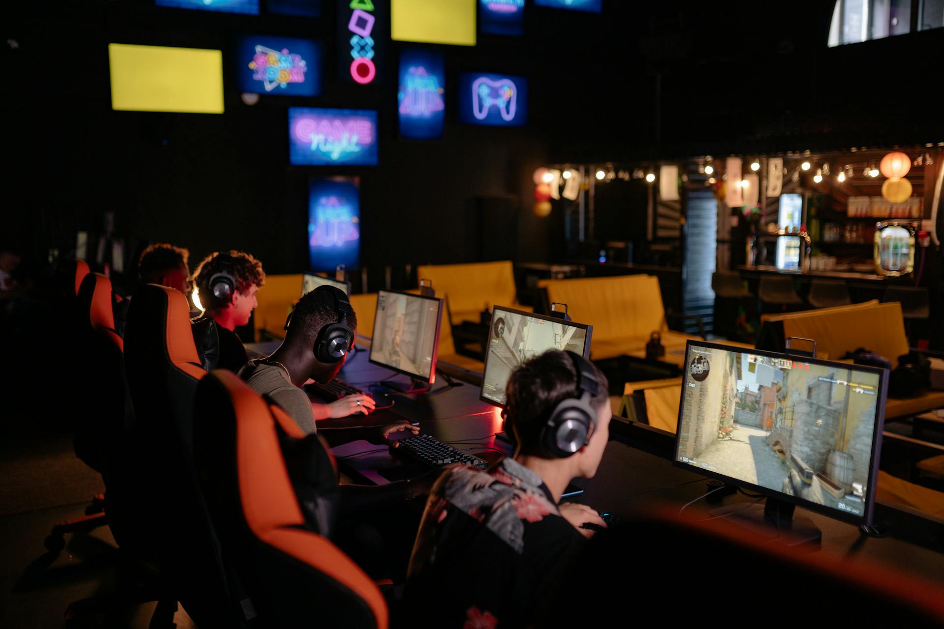 Group of gamers participating in an online tournament at a modern internet cafe.