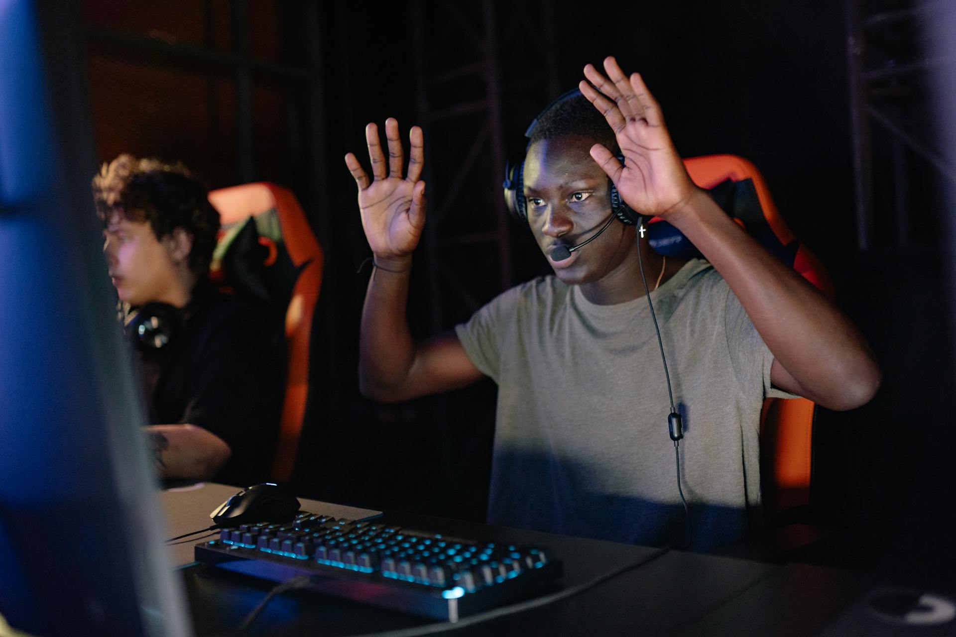 African American gamer raising hands while playing on his PC in a gaming tournament.