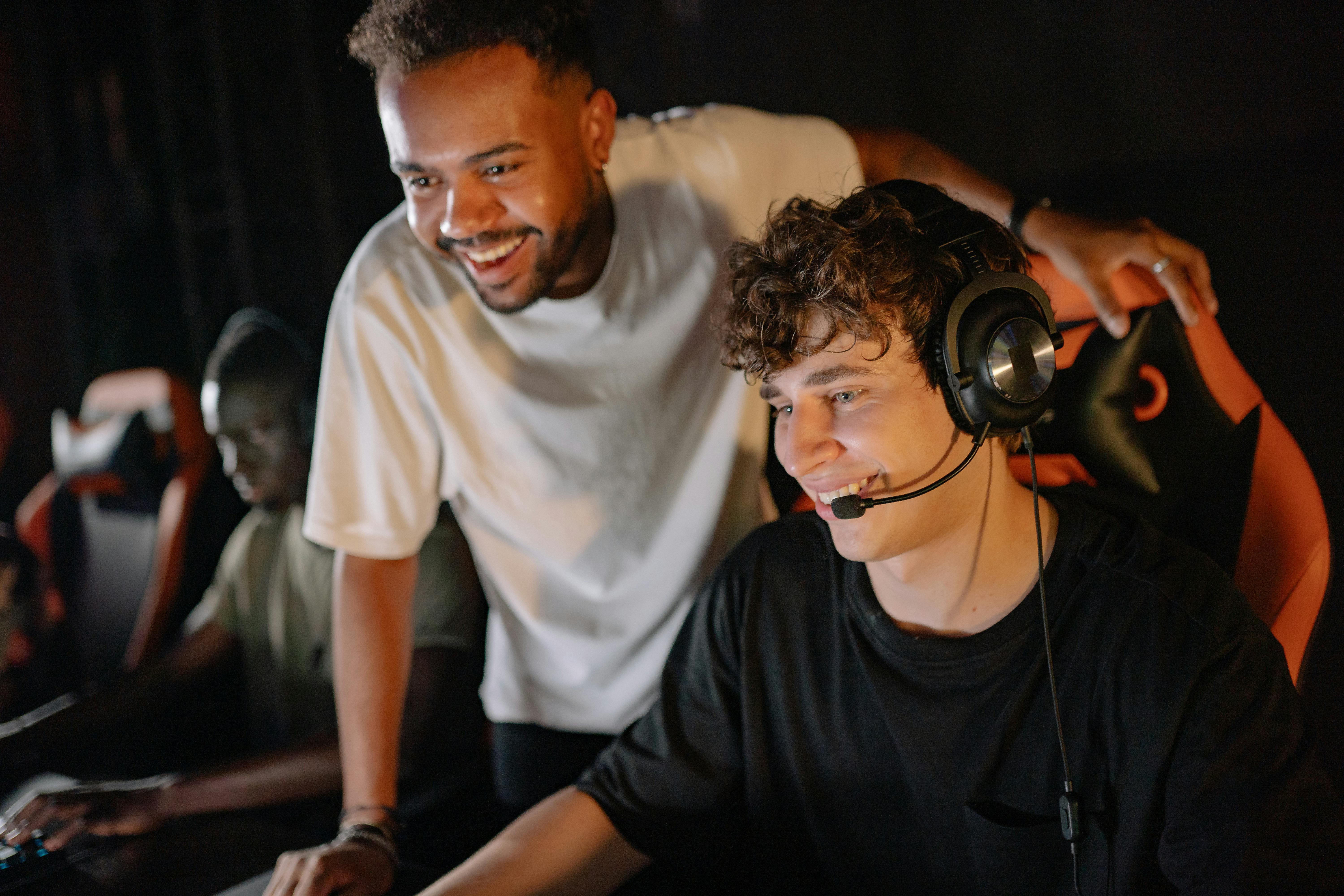 Young men smiling and enjoying a gaming session indoors with headsets.