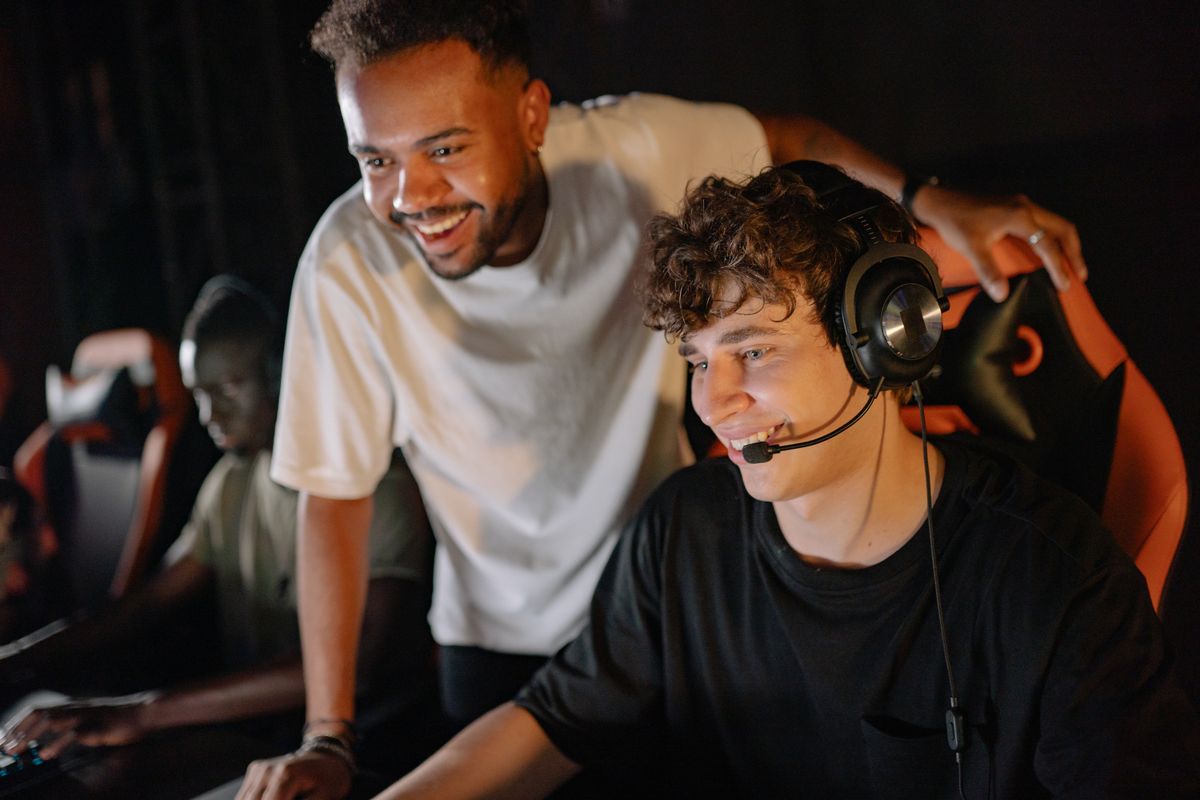 A coach leaning over a player at a gaming station