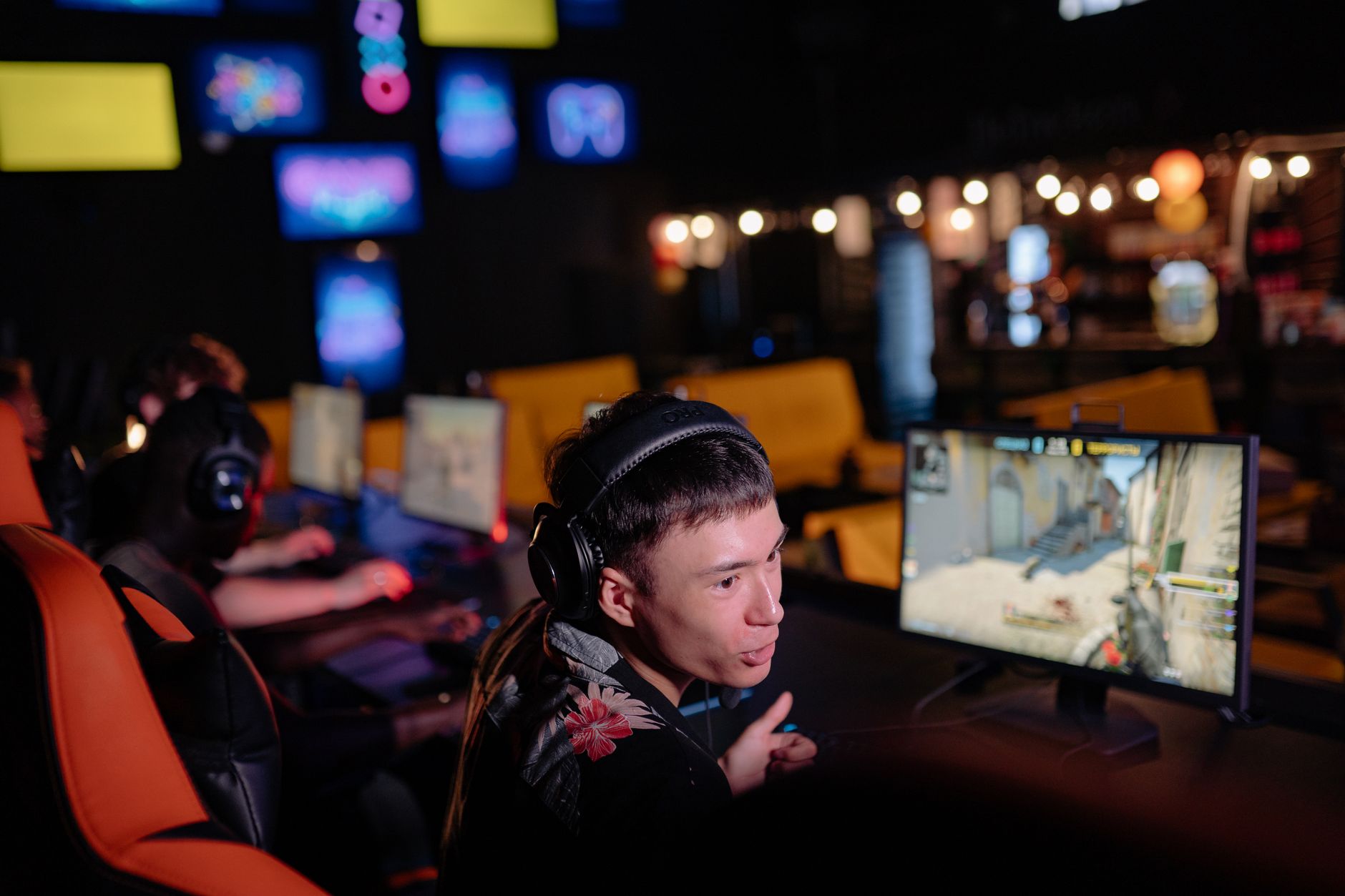Young adults engaged in competitive gaming at an atmospheric cybercafe, sharing the esports experience.