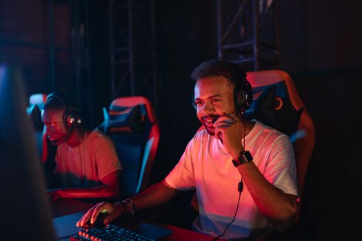 Two gamers immersed in an esports tournament, focused with headsets and keyboards.