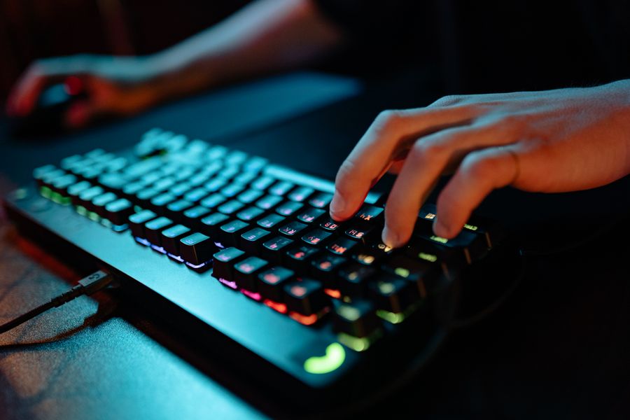 Hands typing on a glowing RGB keyboard during a gaming session