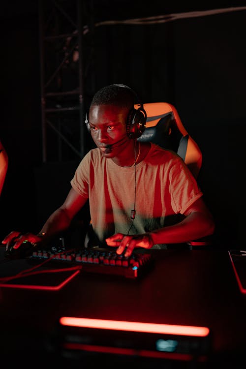 Photo of a Man with a Black Headset Playing on a Computer