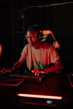 Young adult man gaming intensely at a computer setup with vivid red lights.