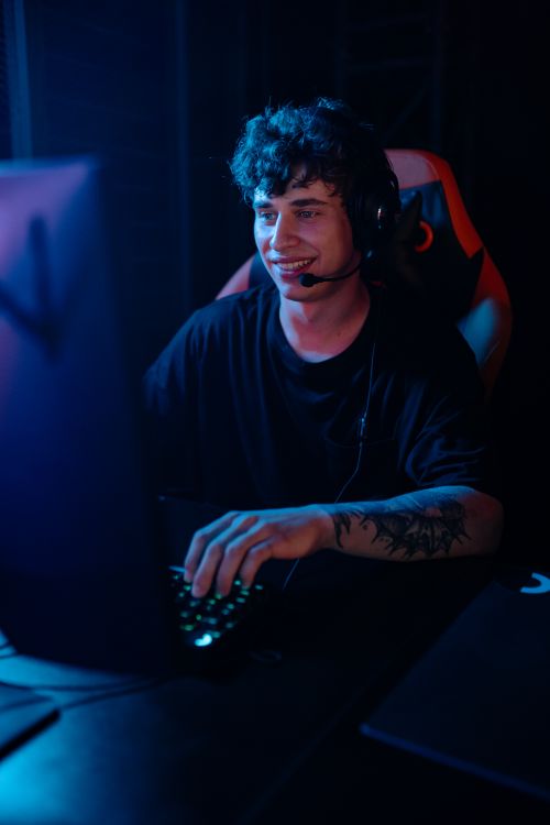 Free Energetic young man engaged in e-sports gaming with headphones. Stock Photo